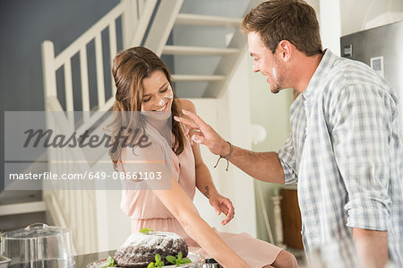 Couple playing around with icing sugar in kitchen