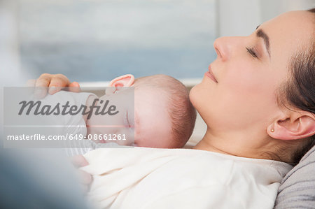 Mother and baby boy sleeping together on bed