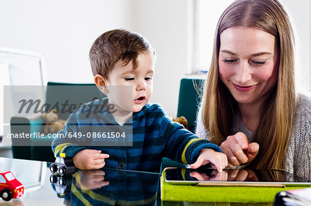 Mid adult woman and baby son using touchscreen on digital tablet at table