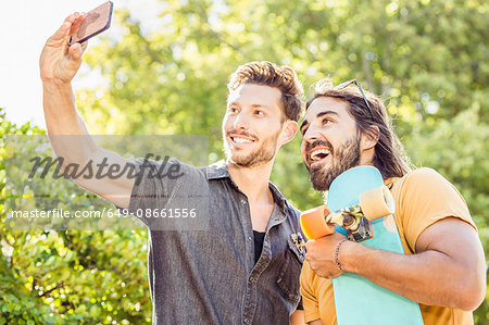 Man and skateboarder friend taking smartphone selfie in park, Franschhoek, South Africa