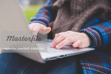 Young woman using laptop, outdoors, close-up