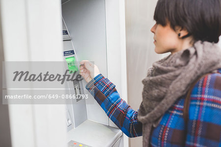 Young woman using cash machine, rear view