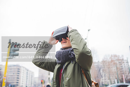 Young woman outdoors, wearing virtual reality headset
