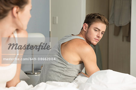 Unhappy young couple getting up from bed