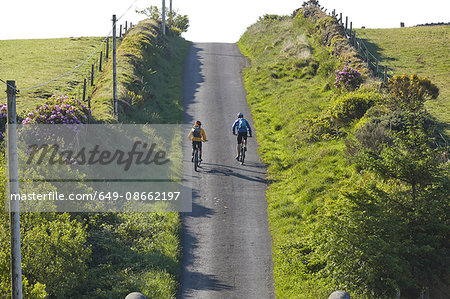 Rear view of cyclists cycling on steep rural road