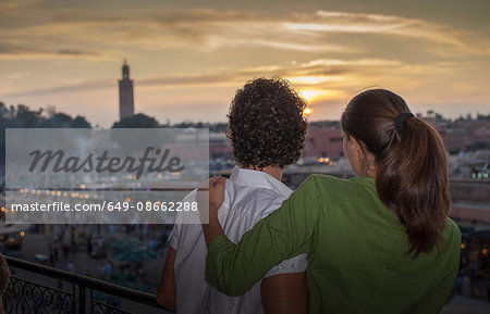 Rear view of couple looking at sunset over Jemaa el-Fnaa Square at sunset, Marrakesh, Morocco