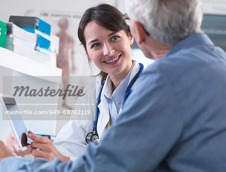 Doctor sharing health information on digital tablet with patient in clinic Doctor sharing health information on digital tablet with patient in clinic