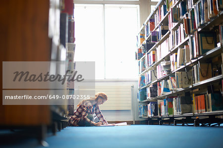 Young female college student working on library floor