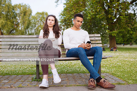 Young couple on park bench holding smartphone