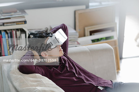 Young man on sofa wearing virtual reality headset