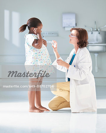 Girl listening to doctors stethoscope in hospital children's ward