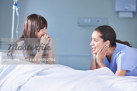 Girl patient talking to female nurse in hospital children's ward Girl patient talking to female nurse in hospital children's ward
