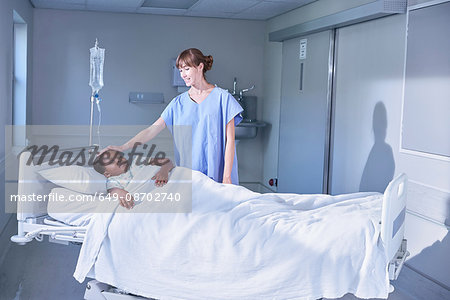 Nurse tending girl patient in bed on hospital children's ward Nurse tending girl patient in bed on hospital children's ward