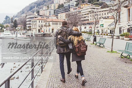 Rear view of young couple strolling along lakeside, Lake Como, Italy