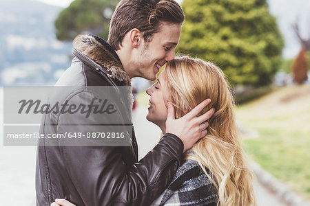 Romantic young man kissing girlfriends forehead, Lake Como, Italy