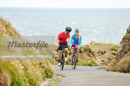 Cyclists riding on road overlooking ocean