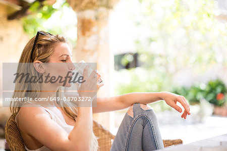 Young woman relaxing on garden patio drinking water