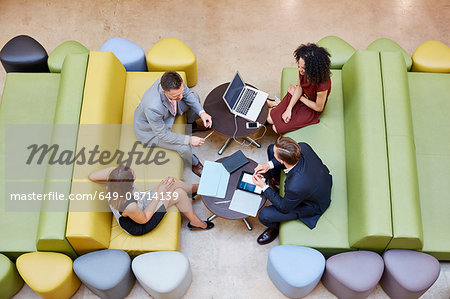 Overhead view of businessmen and businesswomen meeting on design studio sofas