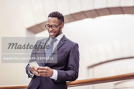 Businessman reading smartphone update on office balcony