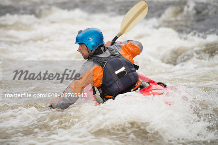Rear view of male kayaker paddling River Dee rapids