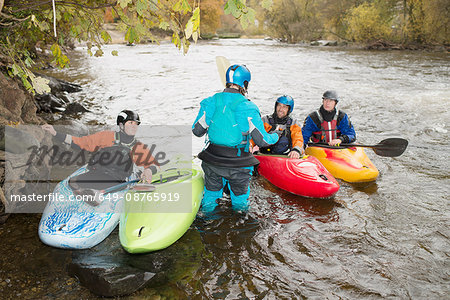 Male and female kayakers having team talk on River Dee, Llangollen, North Wales
