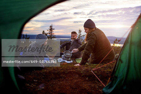 Hikers preparing meal, chatting in front of tent, Keimiotunturi, Lapland, Finland Hikers preparing meal, chatting in front of tent, Keimiotunturi, Lapland, Finland