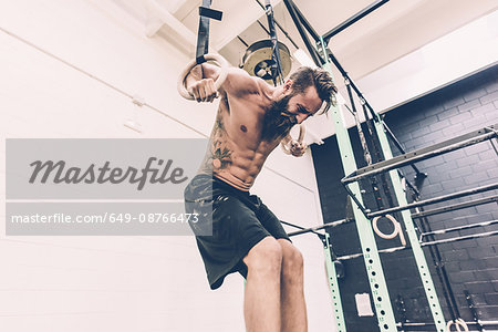 Young male cross trainer training on gymnastic rings