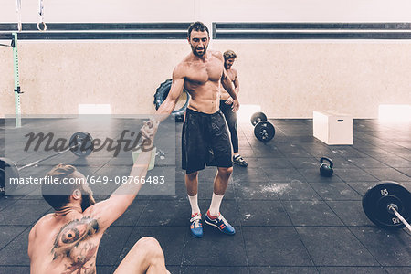 Male cross trainer taking a water break from weightlifting in gym