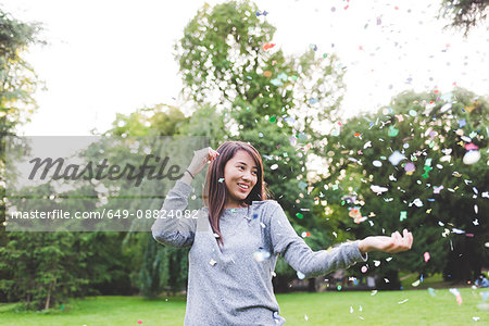 Young woman in park throwing confetti