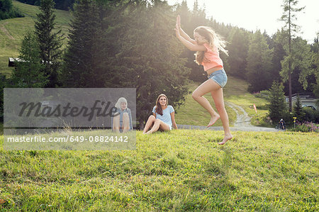 Young woman poised to cartwheel in field, Sattelbergalm, Tirol, Austria