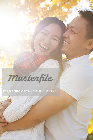 Young couple hugging in sunlit autumnal park, Beijing, China