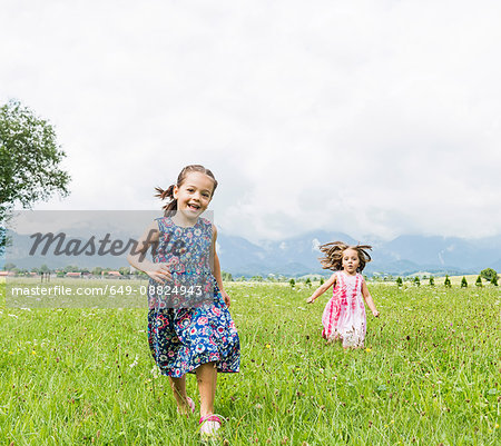 Girls running in field, Fuessen, Bavaria, Germany