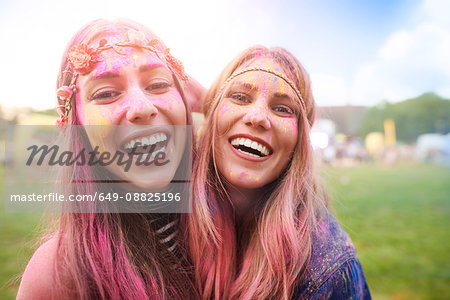Portrait of two female friends at festival, covered in colourful powder paint