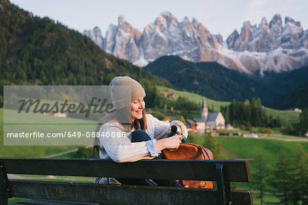 Woman relaxing on park bench, Santa Maddalena, Dolomite Alps, Val di Funes (Funes Valley), South Tyrol, Italy