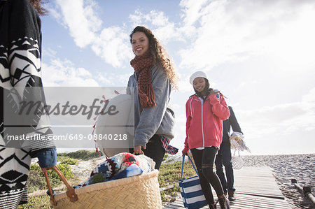 Young adult picnicking friends strolling along beach boardwalk, Western Cape, South Africa