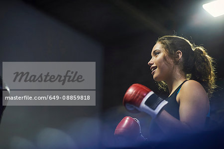 Young female boxer having boxing match in ring