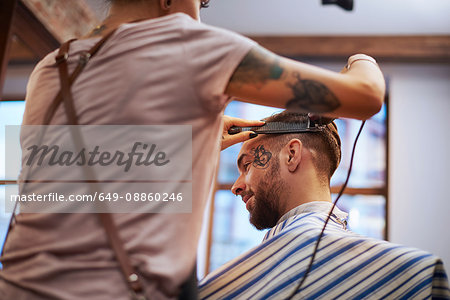 Hairdresser shaving customer's hair
