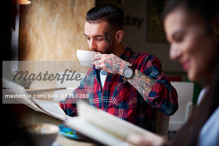 Couple drinking coffee reading newspapers