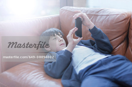 Boy playing with smartphone on sofa