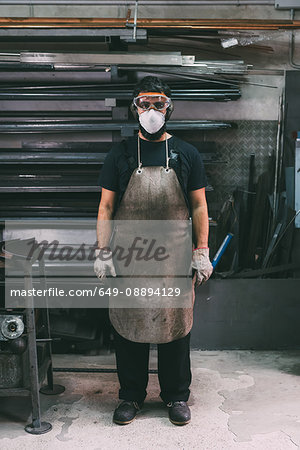 Portrait of male metalworker in dust mask, forge storeroom