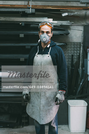 Portrait of metalworker in dust mask in forge workshop