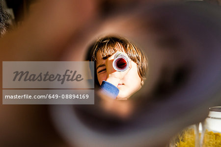 Portrait of boy looking at camera through rolled paper