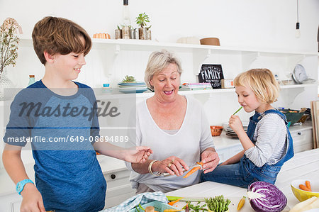 Senior woman and grandchildren preparing vegetables at kitchen table