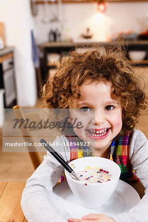 Portrait of girl with toothy grin having cereal in kitchen