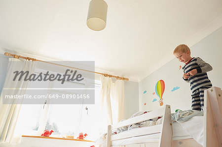 Boy standing on top of bunk bed