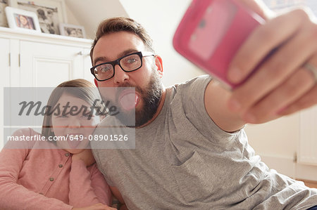 Mid adult man and daughter taking smartphone selfie