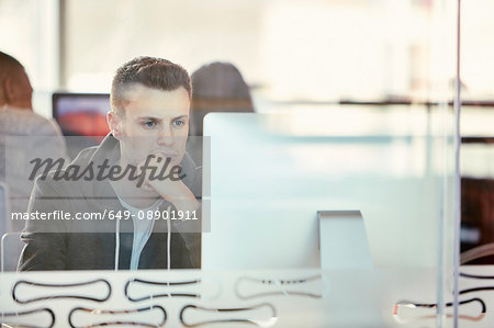 University student working at computer behind glass partition