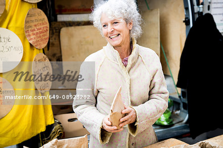 Mature female stall holder selling dried foods at local french market