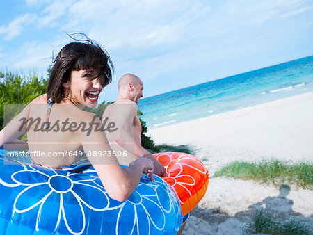 Couple in floats running down to the beach, Mallorca, Spain