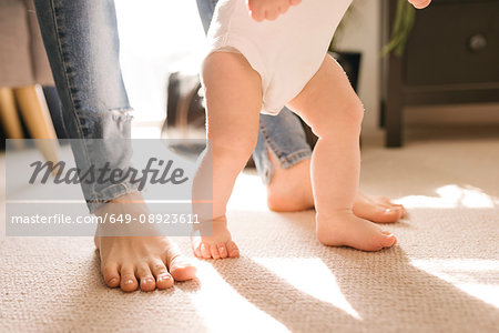 Mother and baby's bare feet on carpet in living room